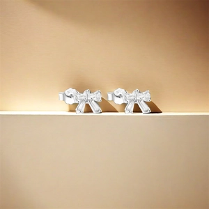 Close-up of S925 sterling silver bow earrings with sparkling zircon on champagne metal