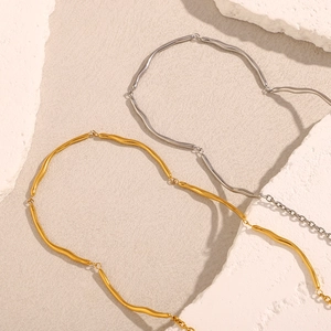 Detail of 18K gold and silver wavy link necklaces on natural stone textures