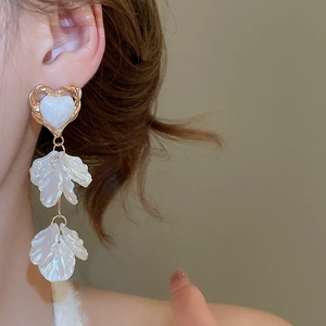 Close-up of elegant floral tassel earrings with heart-shaped studs on a model