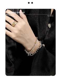 Detail of S925 silver chain bracelet and textured ring worn on model with dark background