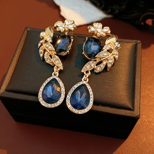 Détail macro de boucles d'oreilles vintage dorées avec pierres bleues sur un coffret