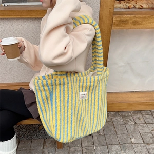 Détail du sac cabas en peluche à rayures jaunes et bleues avec texture douce et étiquette