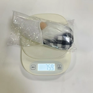 Mesure du poids d'un gnome de Noël debout en vêtements à carreaux sur une balance digitale