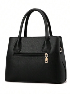 Détail du sac à main noir en cuir grainé avec poche zippée dorée à l'arrière du sac