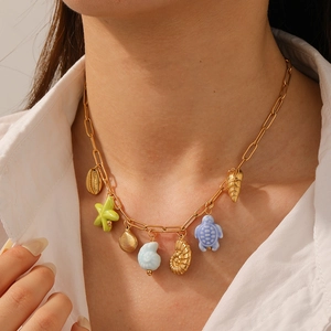 Gold plated ocean theme necklace with starfish turtle and shell pendants on a model