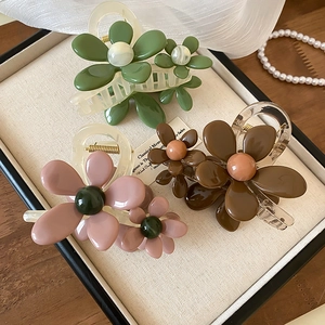 Eleganti mollette per capelli a fiore in resina Morandi su un vassoio di legno strutturato