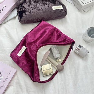 Detail of open crushed velvet cosmetic bags in purple and mauve showing interior capacity