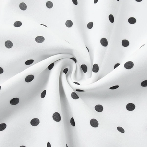 Macro shot of white fabric with black polka dots showing soft texture and fluid drape