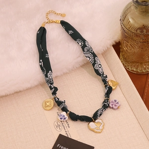 Detail of vintage fabric necklace featuring rose heart charms on a white faux fur backdrop
