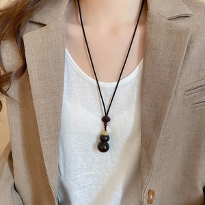 Close-up of ebony wood gourd pendant necklace on model with black waxed cord