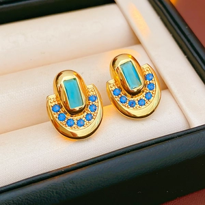 Détail de boucles d'oreilles vintage dorées avec zircons bleus dans un écrin