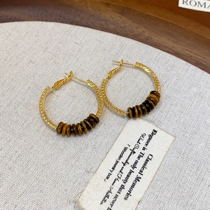 Vintage Goldene Creolen mit braunen Tigerauge-Perlen auf strukturiertem Leinen