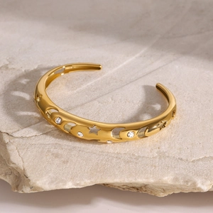 Close-up of golden bangle featuring hollow star-moon patterns and small white rhinestones