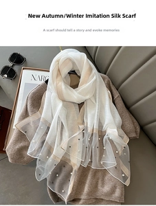 Detail of silk-like striped scarf with elegant pearl bead trim on knitwear