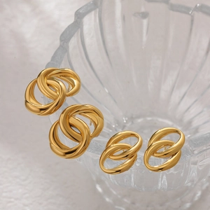 Close-up of 18K gold-plated intertwined hoop earrings hanging on clear textured glass