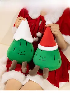 Close-up of a model holding a cute green Christmas tree plush toy with a red festive hat