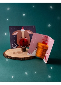 Close-up of 3D Christmas cards with reindeer and gift box designs on wood slices