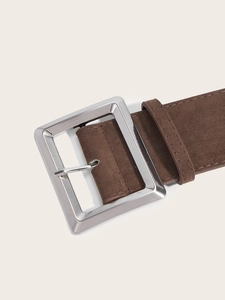 Détail d'une ceinture marron en daim avec une boucle rectangulaire en métal argenté