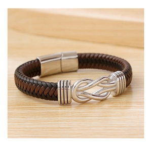 Macro shot of brown braided leather bracelet with silver magnetic buckle on wooden table