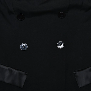 Detailed close-up of black double-breasted dress buttons and satin-trimmed pocket flaps