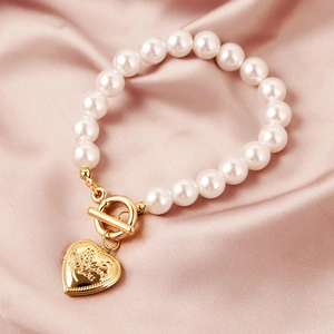 Detailed close-up of Baroque pearl bracelet featuring a gold heart charm and toggle clasp