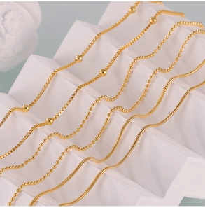 Detailed close-up of golden box chains, bead chains and sleek snake chains on white steps