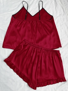 Detail of burgundy satin pajama set featuring black V-neck trim and ruffled shorts hem