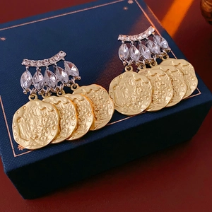 Macro detail of French vintage gold coin earrings with crystal studs on jewelry box