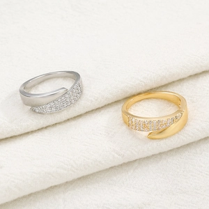 Detailed view of gold and silver open rings with sparkling pavé crystals on fabric