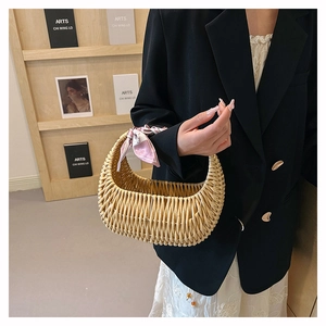 Detail of light brown woven basket bag with pink floral silk scarf tied on handle