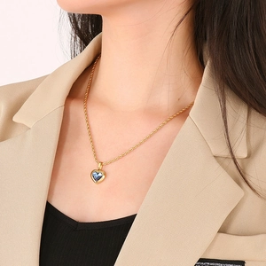 Detailed close-up of a blue faceted heart pendant on a gold twisted chain necklace