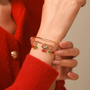 Close-up of Christmas charm bracelet with reindeer pendants on red sweater background