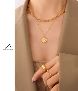 Close-up of layered gold stainless steel necklace with heart pendant and ring on a model