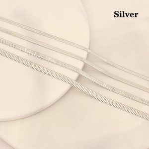 Silver stainless steel flat snake chain necklace set in various widths on a ceramic plate