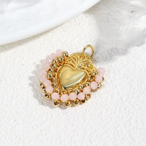 Detailed view of a gold heart pendant with crown decor and pink bead embellishments