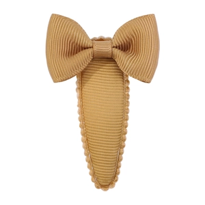 Detail of golden grosgrain ribbon bow hair clip with textured fabric wrapped base
