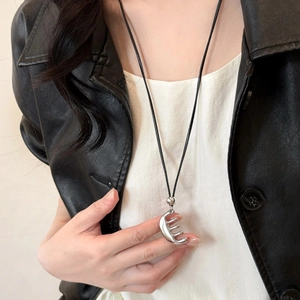 Collier minimaliste avec pendentif peigne argenté et cordon noir sur veste en cuir