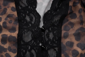 Detail of leopard print fabric with black lace trim and two black buttons on the cardigan