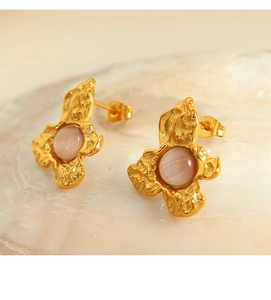 Macro view of gold flower stud earrings with pink cat-eye stone and liquid metal texture