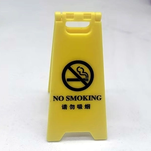 Close-up of a yellow folding warning sign with No Smoking icon and bilingual text