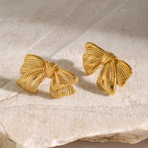 Detailed macro shot of 18k gold stainless steel bow earrings with brushed metal texture