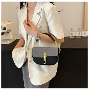 Close-up of black leather and grey fabric patchwork handbag with golden chain handle