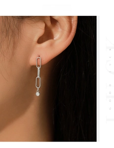 Macro shot of silver paperclip chain earrings with dangling D color moissanite