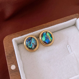 Detail of 18K gold plated oval earrings with iridescent shell in a wooden jewelry box