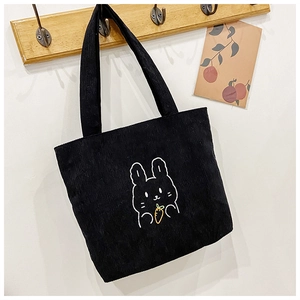 Detail of black corduroy tote bag featuring a cute white rabbit and orange carrot embroidery