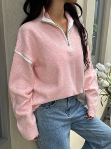 Detail of pink half-zip knit sweater with white striped accents on shoulders and collar
