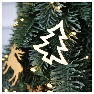Golden wooden reindeer and tree ornaments hanging on green Christmas tree branches
