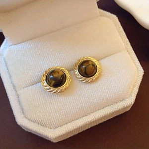 Detail of round tiger eye stone earrings in a velvet jewelry box with golden edges