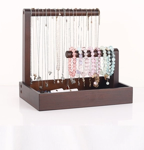 Detail of double-tier dark wood jewelry stand with hanging necklaces and storage tray