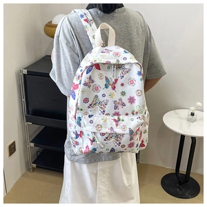 Dettaglio dello zaino bianco con farfalle colorate e fiori indossato da una modella